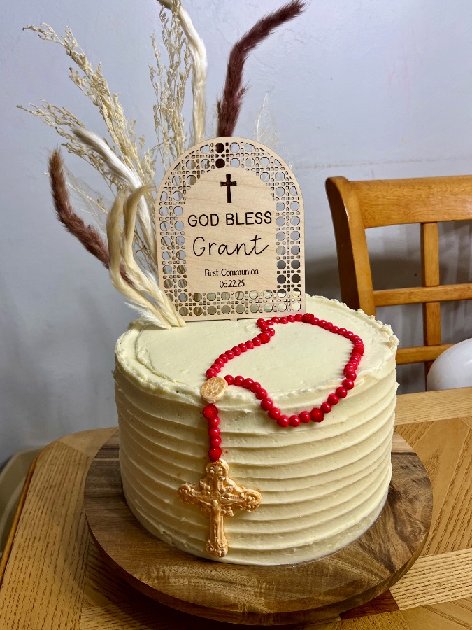 Cream buttercream cake with cascading greenery vines, pink roses, and woodland animal figurines