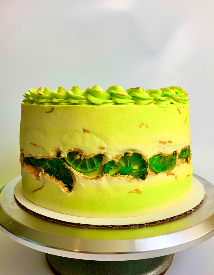 Tall cake covered in blue, pink, and white sprinkles with cream rosettes on top